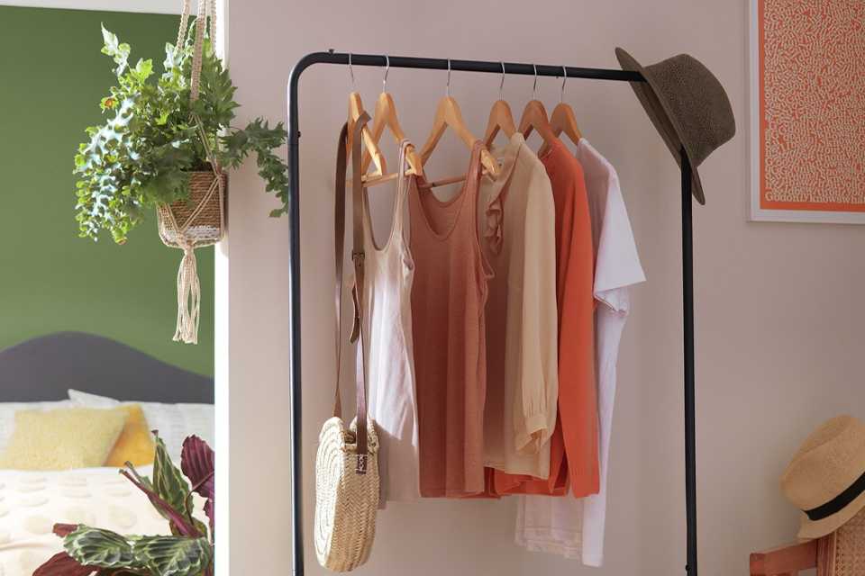 Habitat Arnie Clothes Rail in black colour placed in a hallway with clothes and a hat hung on it.