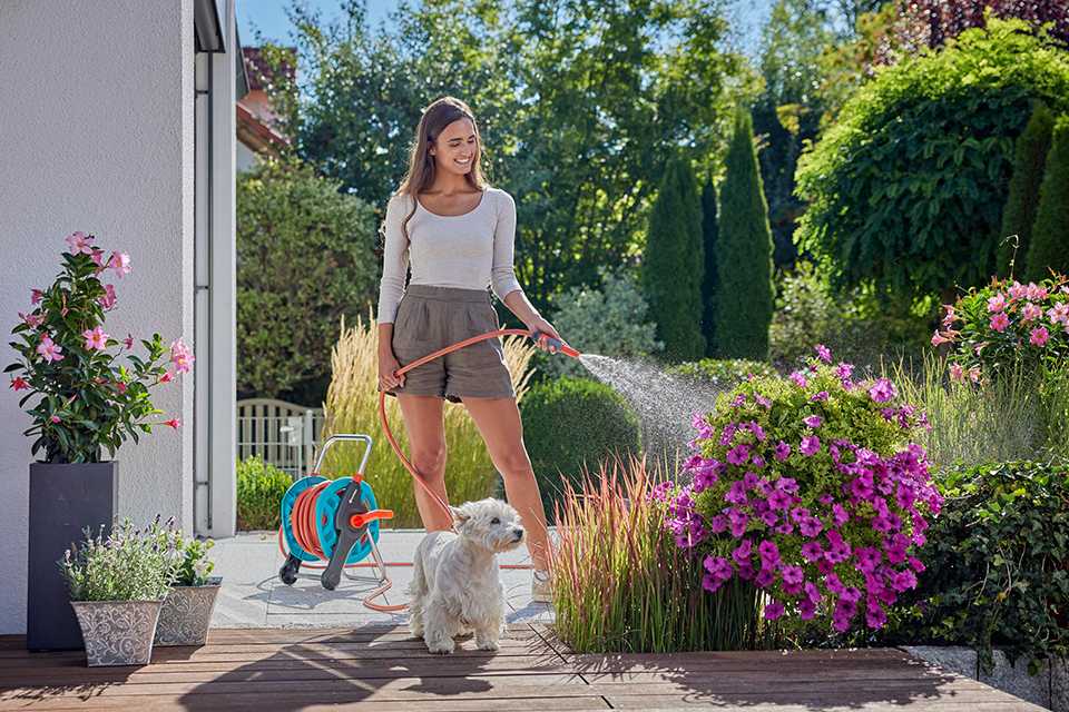A woman using a GARDENA hose for her garden plants.