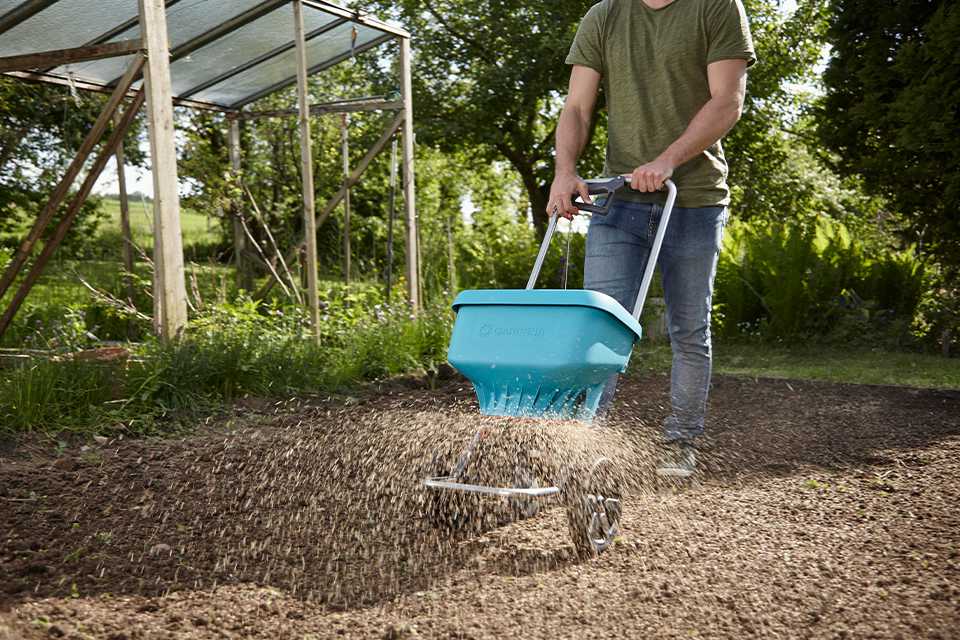 Someone using GARDENA spreader tool in a field.