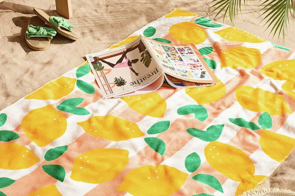 A book on a Habitat lemon skinny stripe beach towel on a beach.