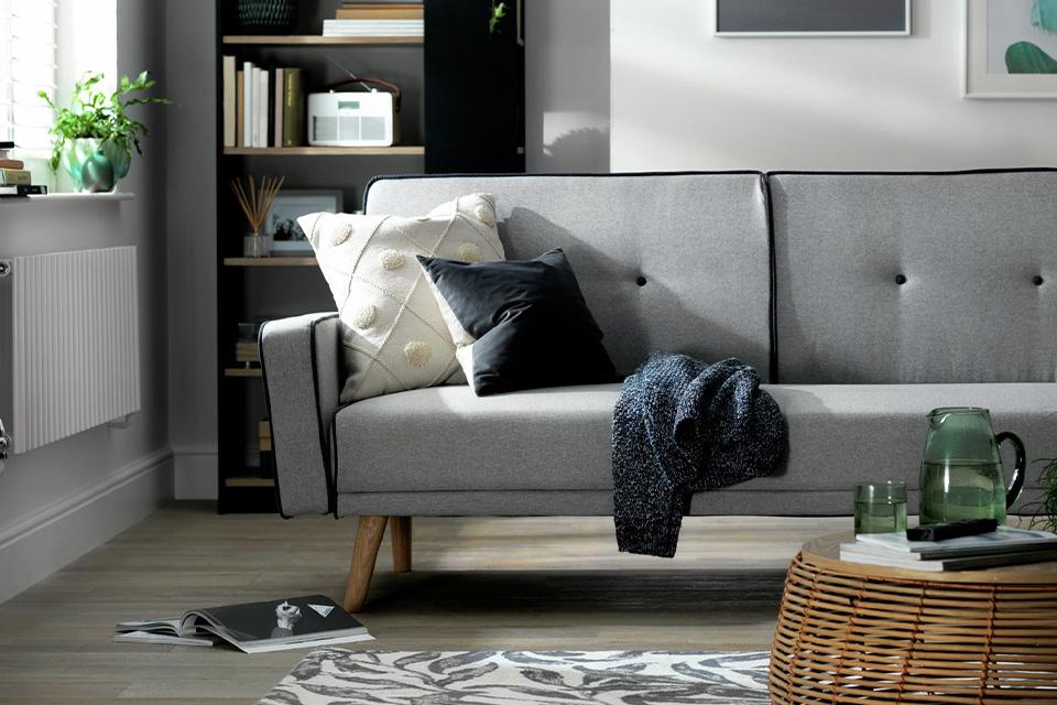 Image of a living room with a small sofa, rug and armchair.