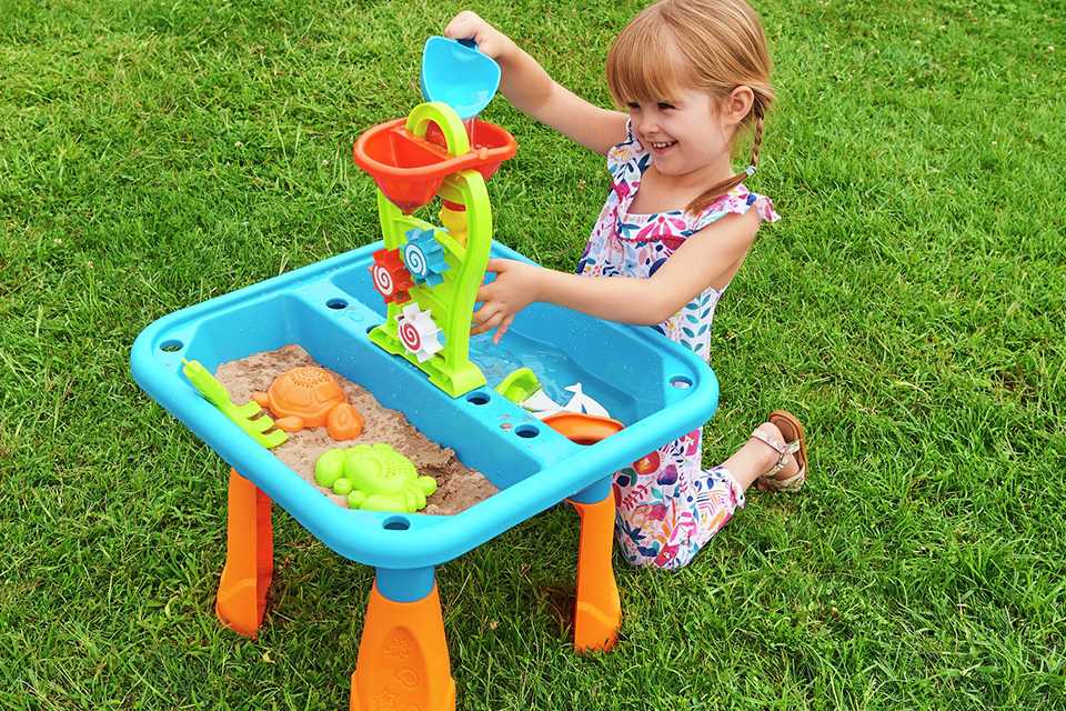 A child playing outdoors with Chad Valley Sand and Water Table.