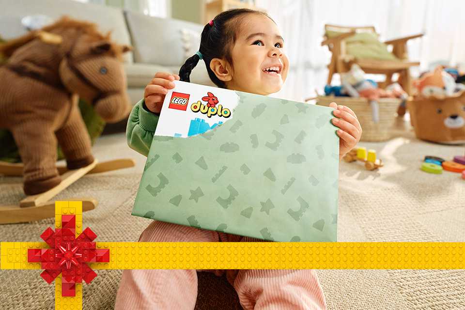 Little girl holding a LEGO® DUPLO present.