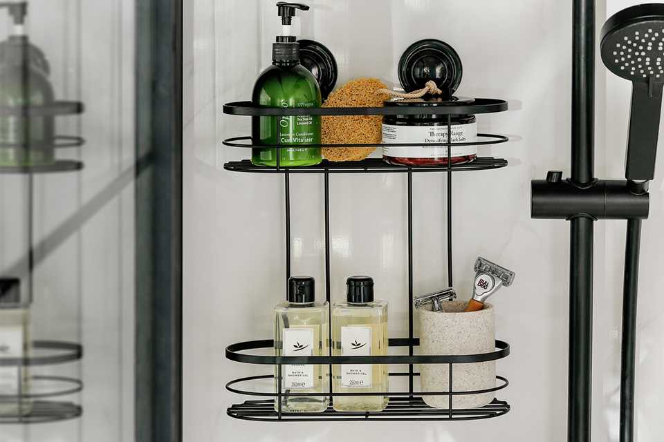 A 2 tier black shower caddy wall mounted in the shower.