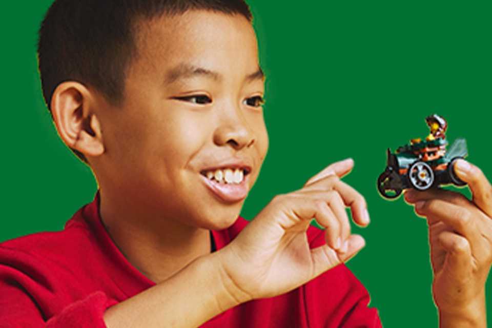 Boy playing with a LEGO® soapbox car toy.