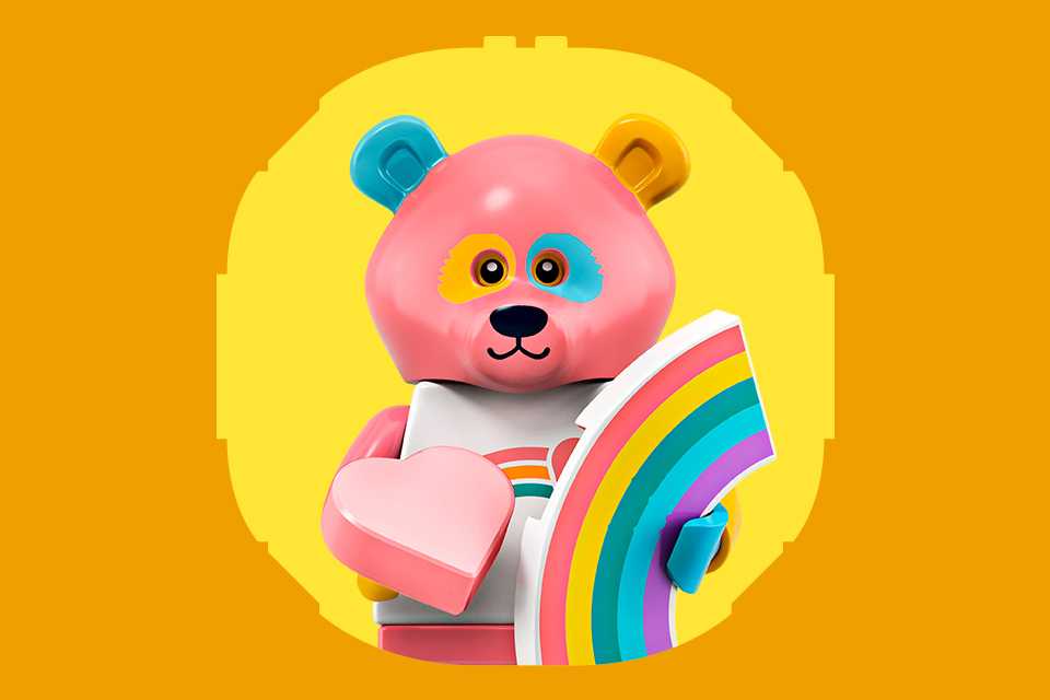 Multicoloured LEGO® minifigure bear holding a rainbow on a yellow and orange background.