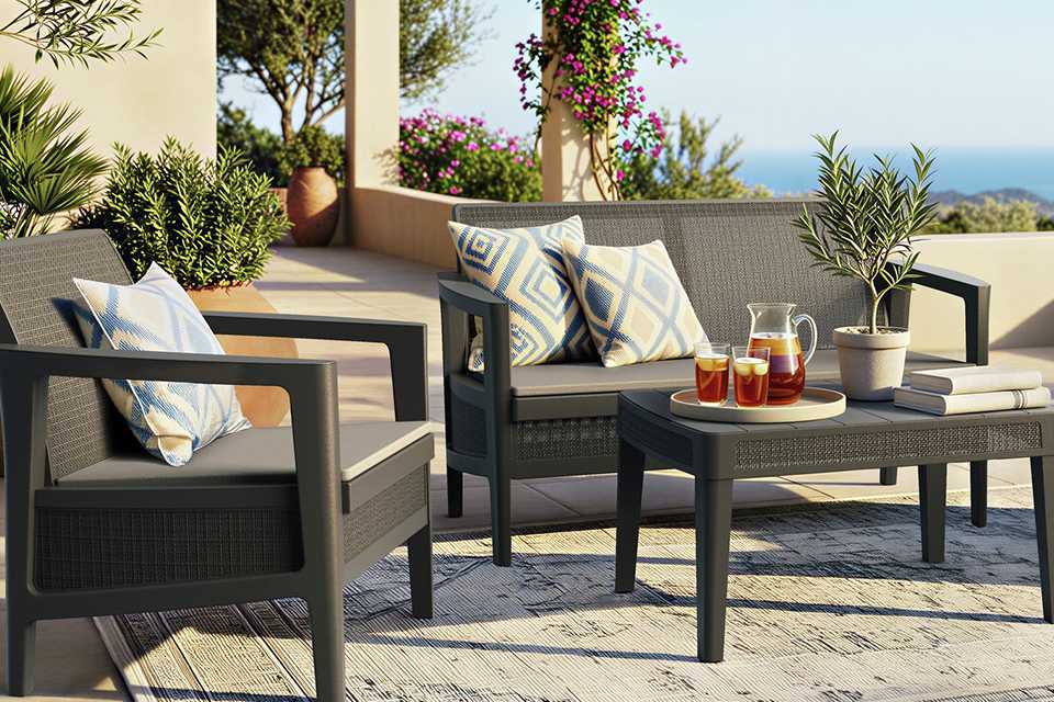 A grey Keter resin lounge set placed outdoors with cushions on top of it.