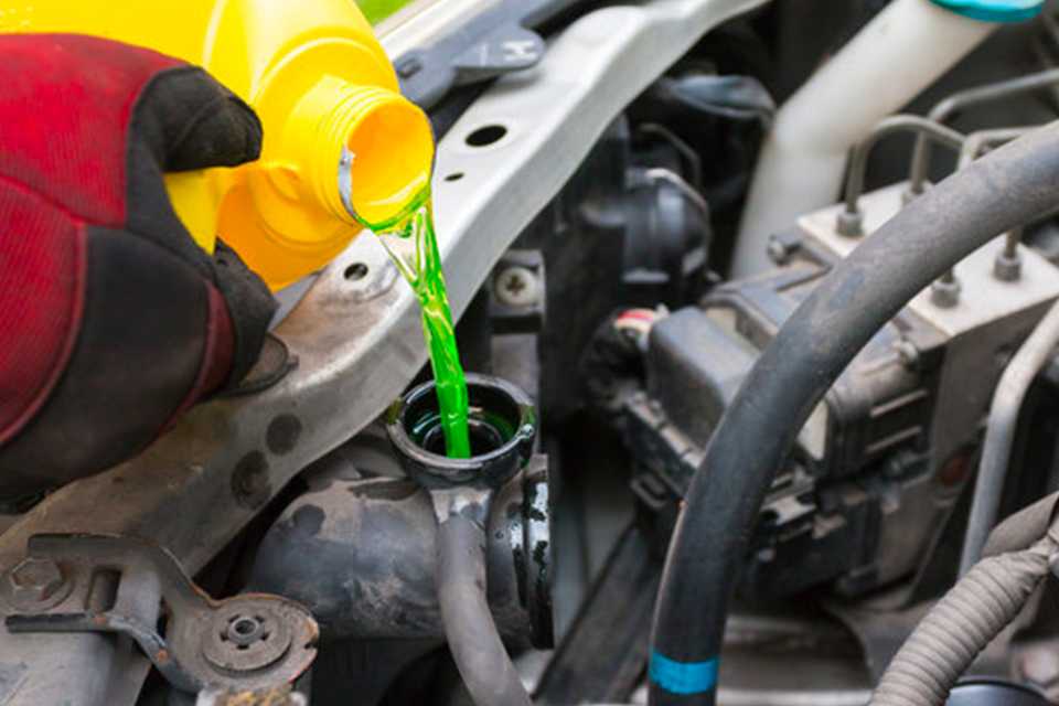 A person pouring coolant in the car.