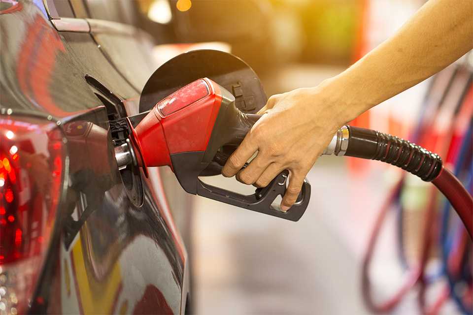 A man pumping fuel in a car at a gas station.