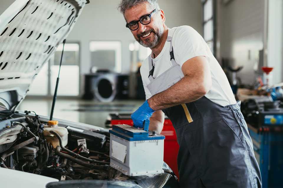 A person removing the car battery from a car.