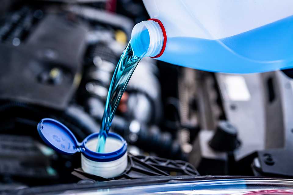 A person pouring screen wash in a car.