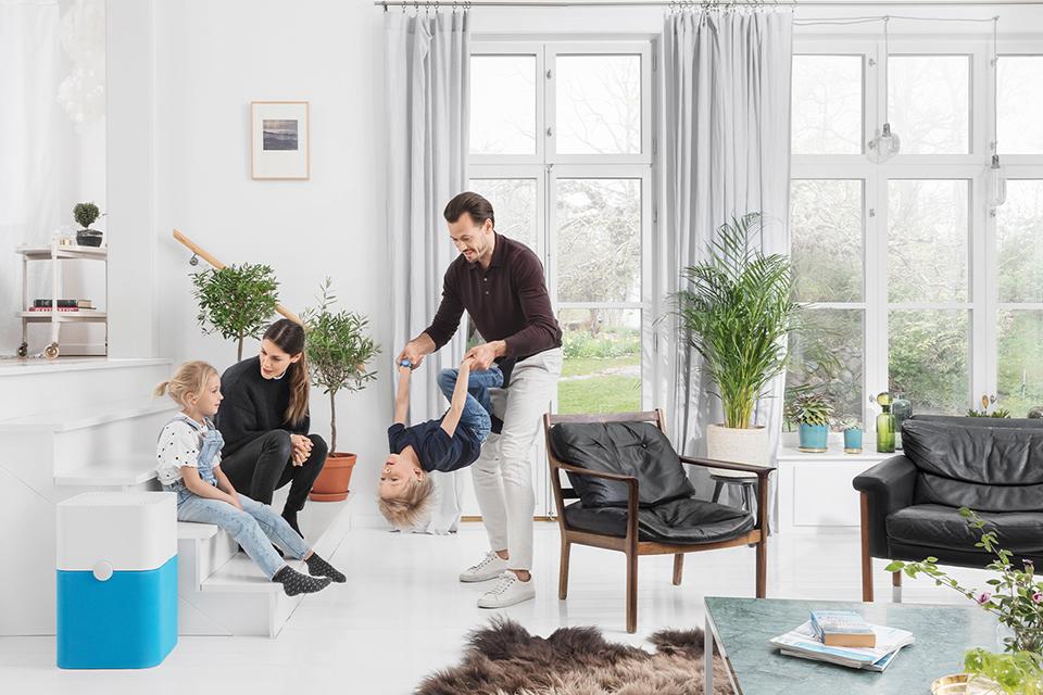 A family sitting and playing in a living room containing an air purifier.