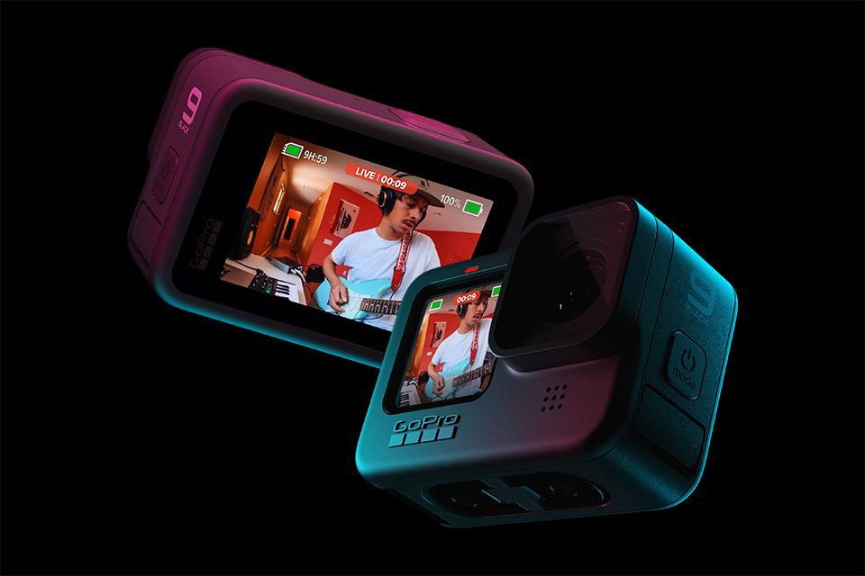 A GoPro Hero9 Black camera is suspended against a black background. On the screen is a figure video streaming.