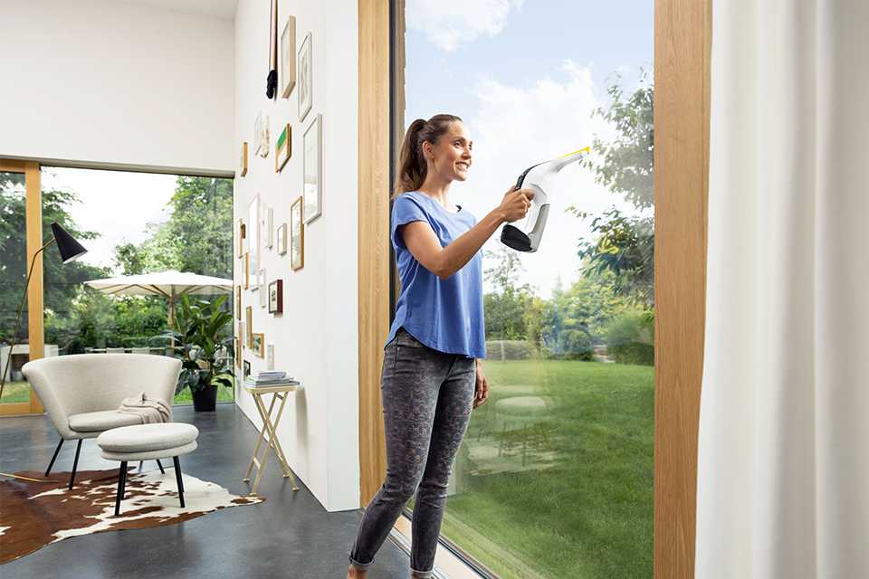 A woman using Kärcher window vacuums on a window.