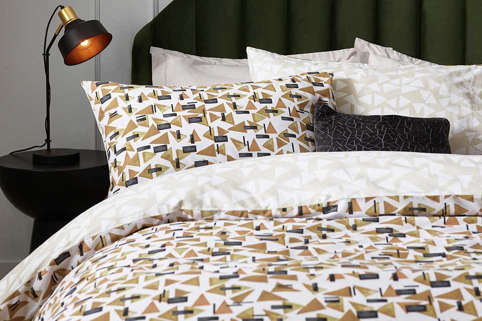 A Home City Printed Toffee Bedding set on a bed in a white bedroom.