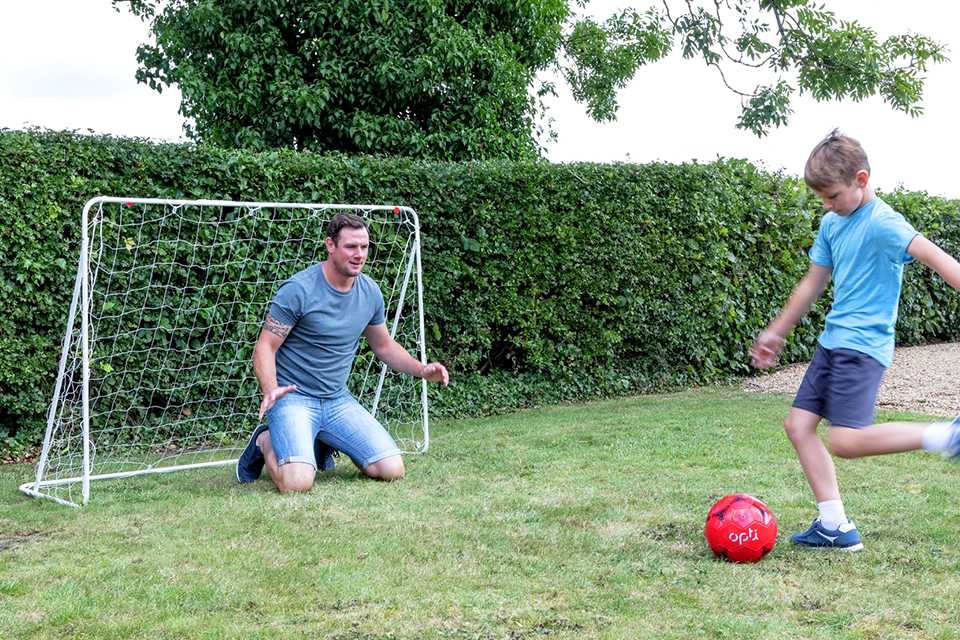 a man and a boy playing football in a garden.