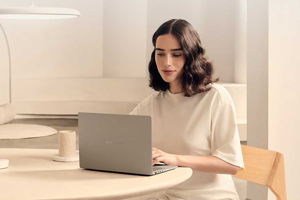 A woman using ASUS Zenbook A14 14in Snapdragon X 16GB 1TB Laptop.