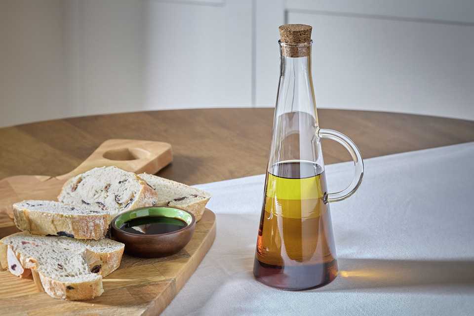 Habitat Tinted Glass Oil Pourer placed next to a wooden platter.