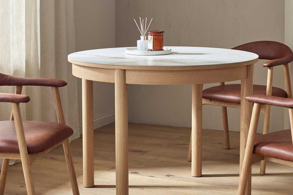 A Habitat Lex ceramic round dining table next to some chairs.
