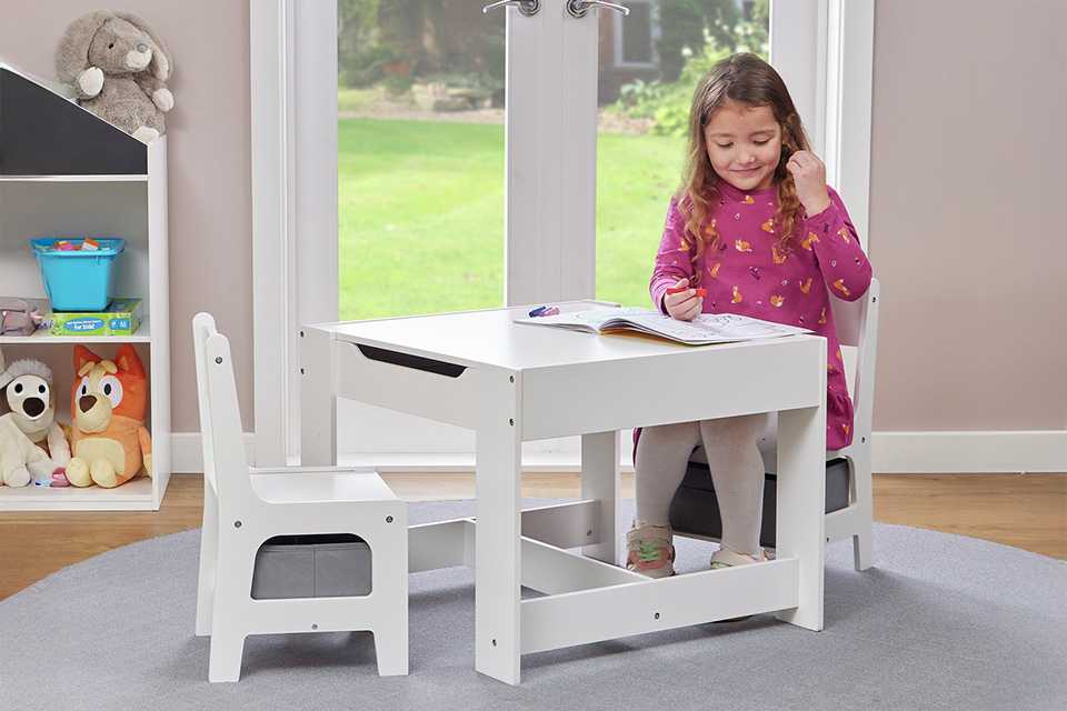 A child sitting at a Liberty House kids' activity table with 2 chairs.