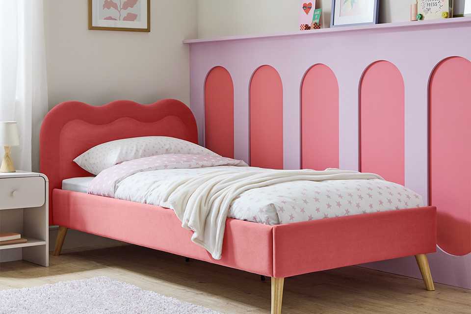 A Habitat kids' pink upholstered bed in a child's room.