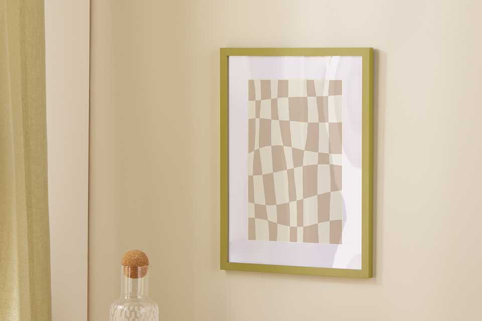 An Argos Home green Picture Frame on a wall right above the side table.