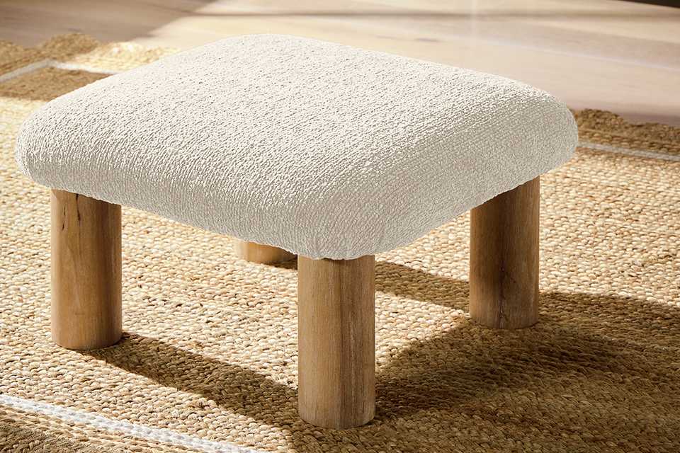 A boucle footstool on a rug.