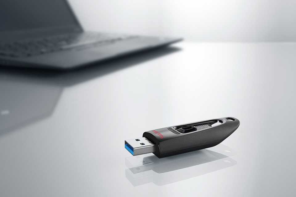 A USB drive kept on a table in front of a laptop.
