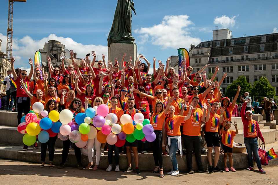 A group of Habitat colleagues holding balloons and flags to show their support for Pride.