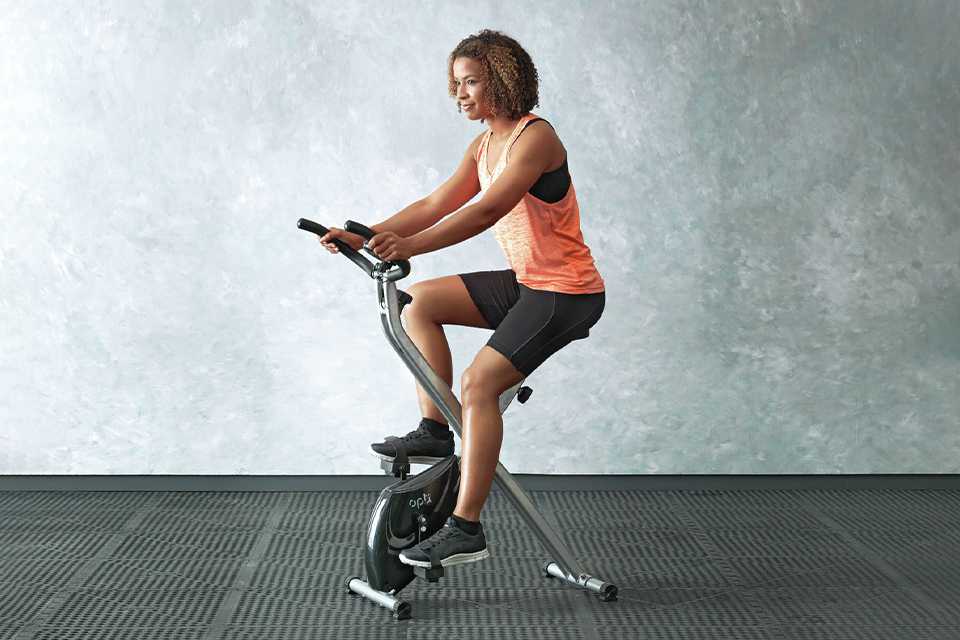 A woman using Opti Folding Magnetic Exercise Bike.