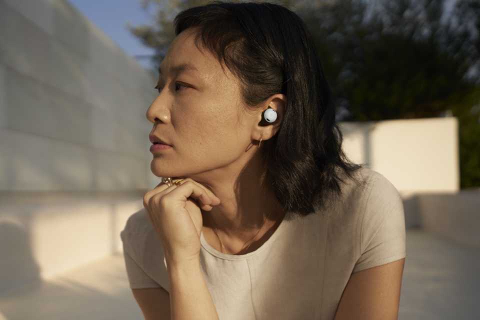 A woman wearing Google Pixel Buds Pro and looking towards her right.