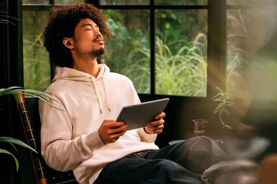 A man holding a Hazel Google Pixel tablet and lounging on a chair.