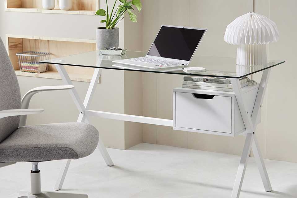 A neat and minimal home office set-up with a glass table and a grey office chair.