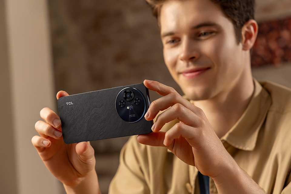 A man clicking a photo with his grey TCL 50 Pro NXTPAPER 5G 512GB smartphone.