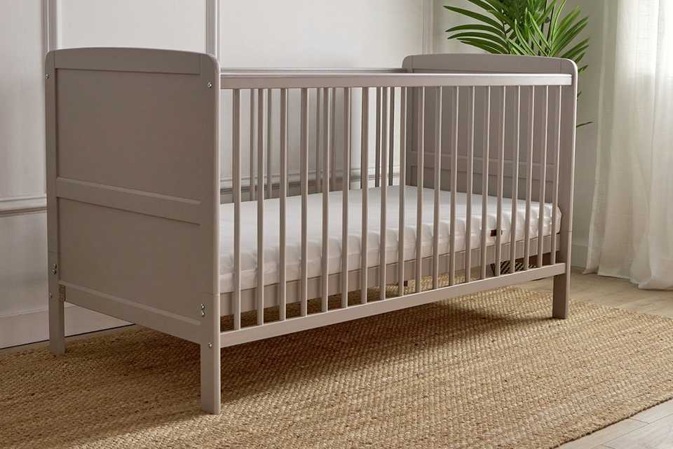 Baby Elegance Travis baby cot bed with mattress in grey in a nursery setup.