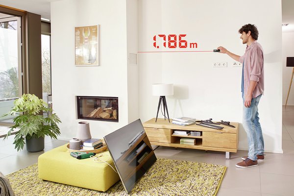 A person using a Bosch Zamo Laser Measure - 25m to check the wall width.