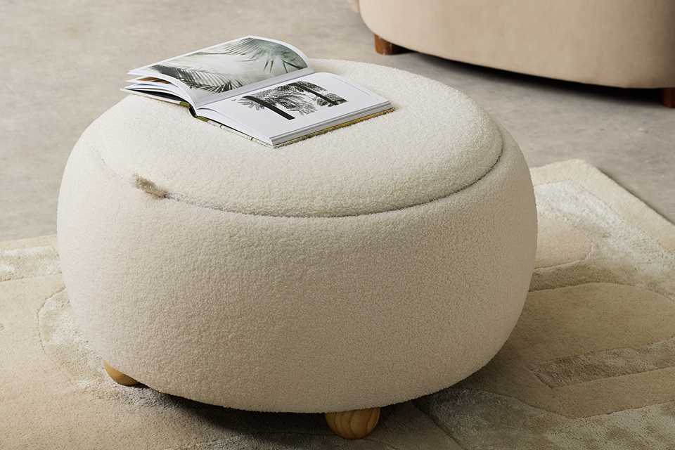 An open magazine on a Habitat Adeline Round Coffee Table - Cream.