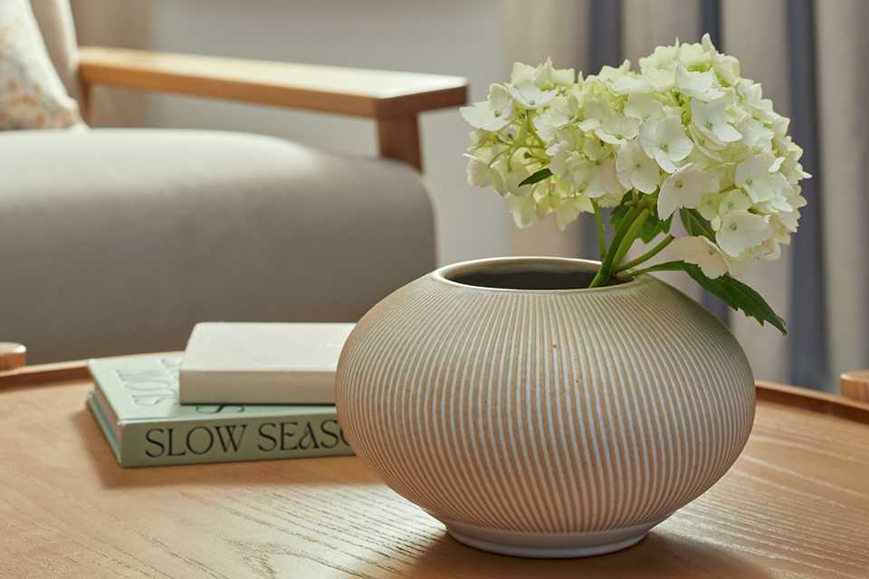 A Habitat small ribbed ceramic vase next to books on a coffee table.