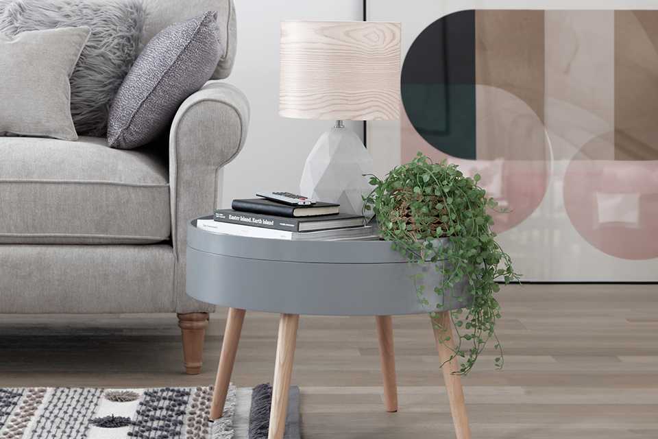 A lamp and faux plant on a Habitat Skandi round coffee table in grey colour.