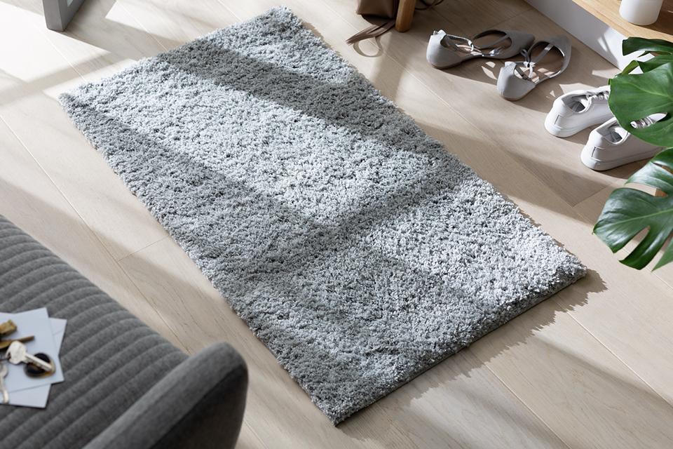 A small grey rug on the floor in a hallway.