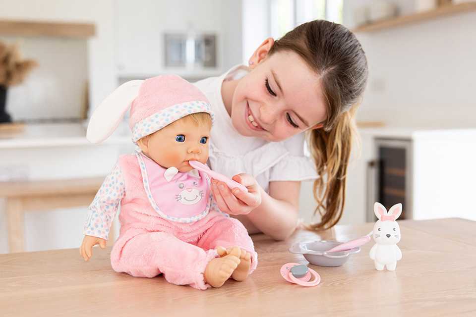 Girl feeding 44cm Tny Treasures baby doll with plastic feeding set.