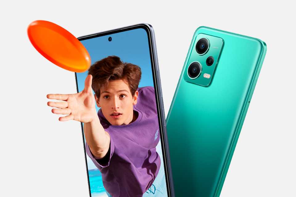 A young man diving for a frisbee coming out of a smartphone screen next to a Redmi Note 12 Pro smartphone.