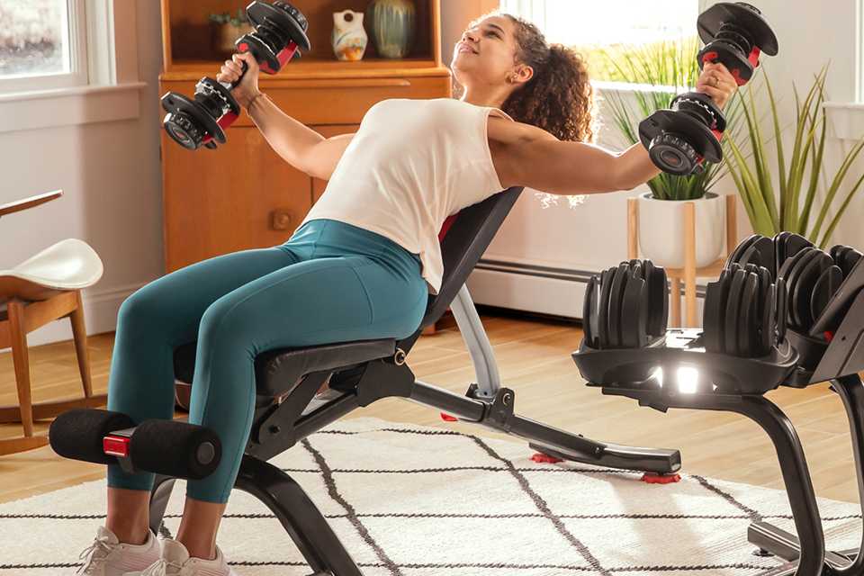 A woman using BowFlex 5.1S Stowable Bench to workout at home.