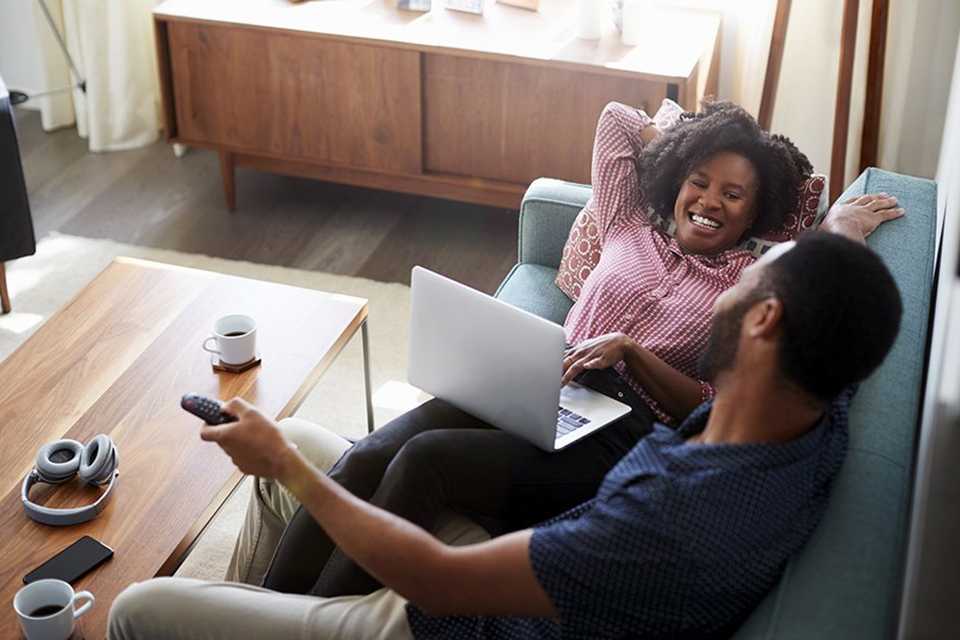 A couple chatting while being on laptop with a headphone and other things lying on the table.