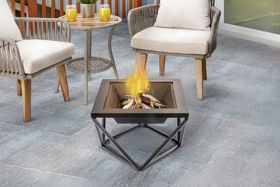 A Teamson Home wood burning fire pit being used outdoors on a patio.