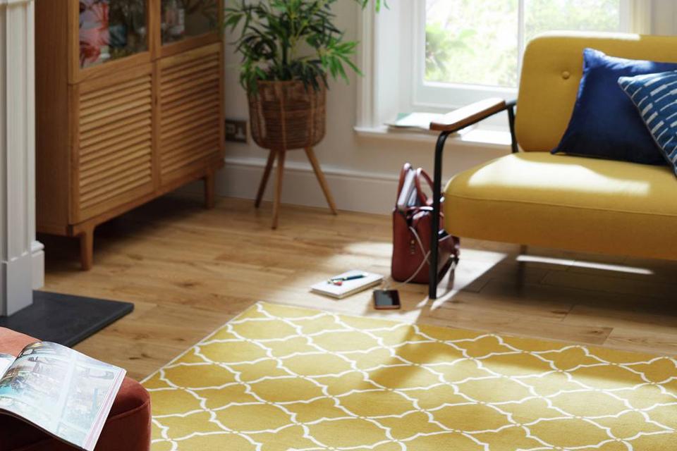 Patterned mustard rug in living room with mustard armchair.