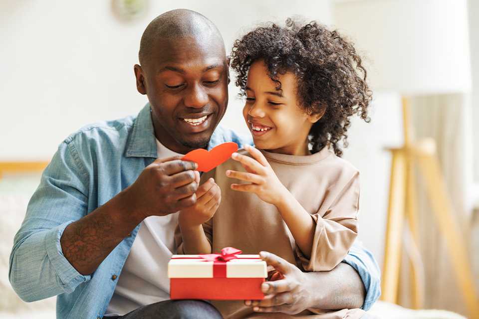 A father and his son opening a present together at home.