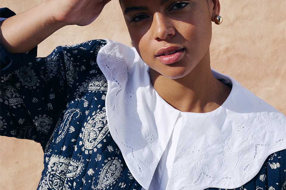 A woman dressed in a white top and a navy printed quilted jacket.