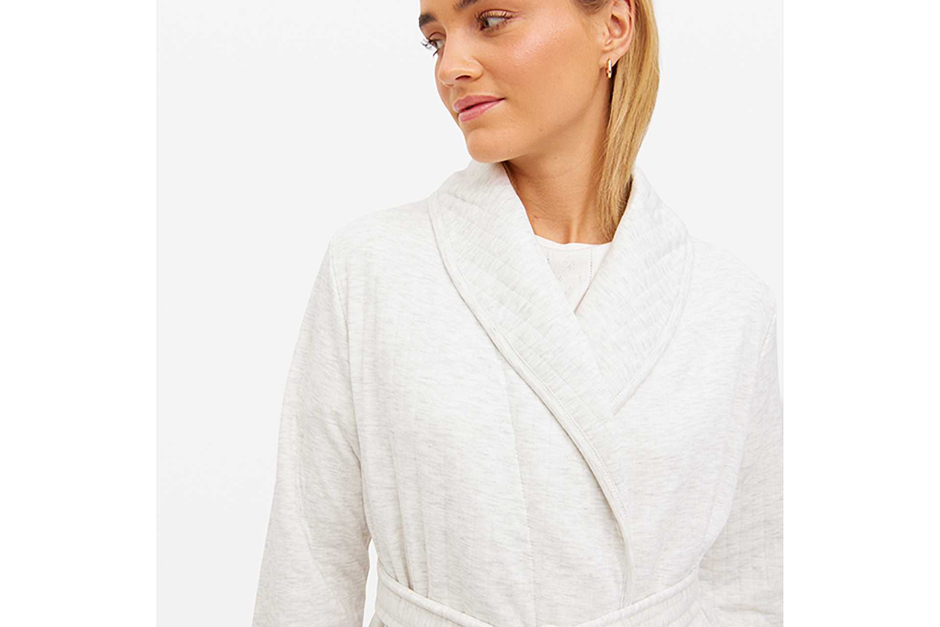 A woman wearing a grey, ribbed dressing gown.