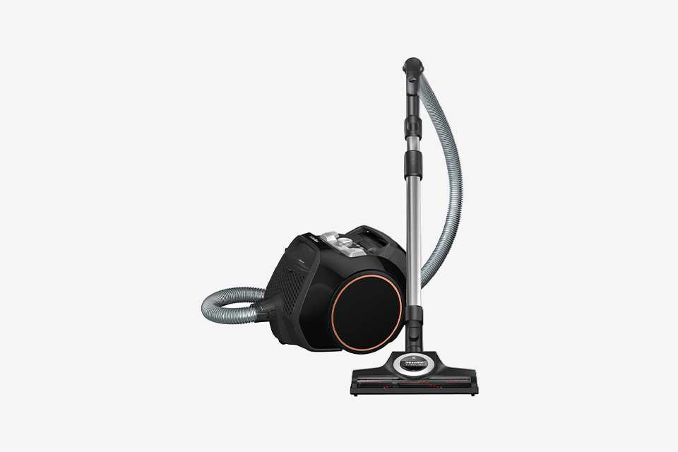 Miele Boost vacuum cleaner in black and rose gold with hose stood up.